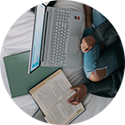 Eine Frau sitzt vor ihrem Laptop und liest nebenbei in Büchern Eine Frau sitzt vor ihrem Laptop und liest nebenbei in Büchern